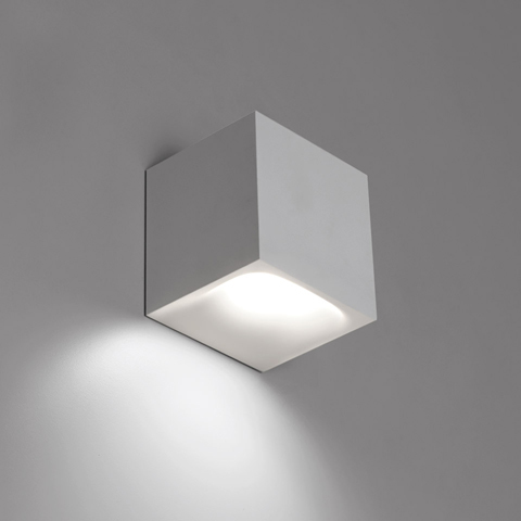 Artemide Aede white cubic wall light emitting downward LED light, casting a warm glow on the wall surface