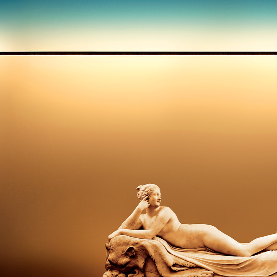 Classical reclining female marble sculpture against a warm golden gradient background, evoking the serene beauty of dusk light