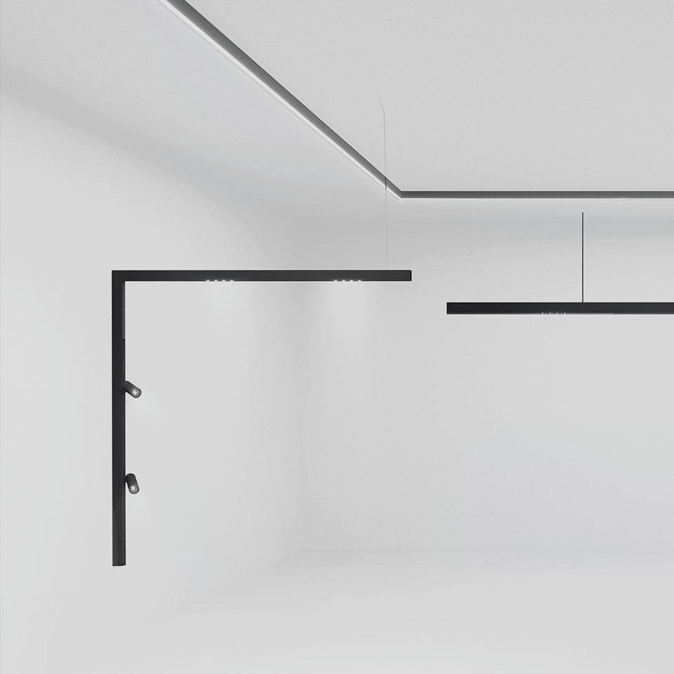 Artemide A.24 black linear wall and pendant lighting system with adjustable spotlights, forming L-shaped and straight configurations in a white room