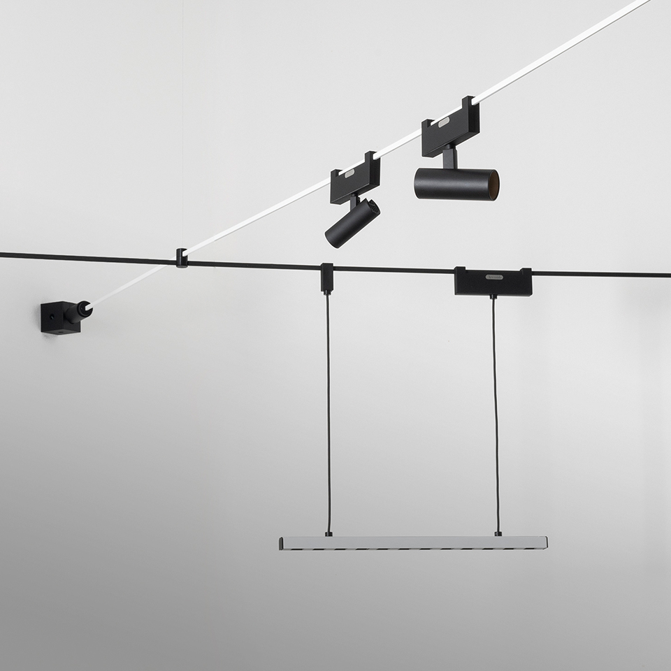 Artemide Funivia system: black cable track with adjustable spotlight and pendant linear LED bar suspended from ceiling