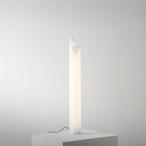 Artemide Chimera floor lamp: tall white sculptural column diffuser emitting soft warm light, with black power cord