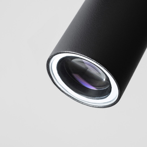 Artemide Coherence spotlight: black cylindrical body with precision optical lens, designed for focused directional lighting