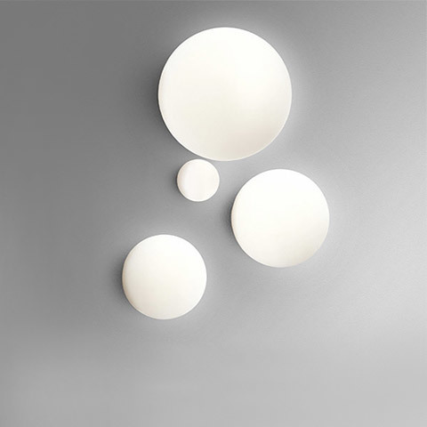 Artemide Dioscuri wall/ceiling lamps: four opal white spherical diffusers in different sizes mounted on a grey wall