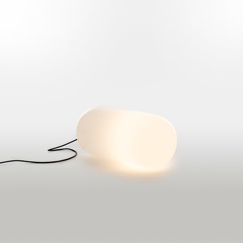 Artemide Gople Outdoor floor lamp with organic pebble-shaped white diffuser emitting warm light, connected by a black cable
