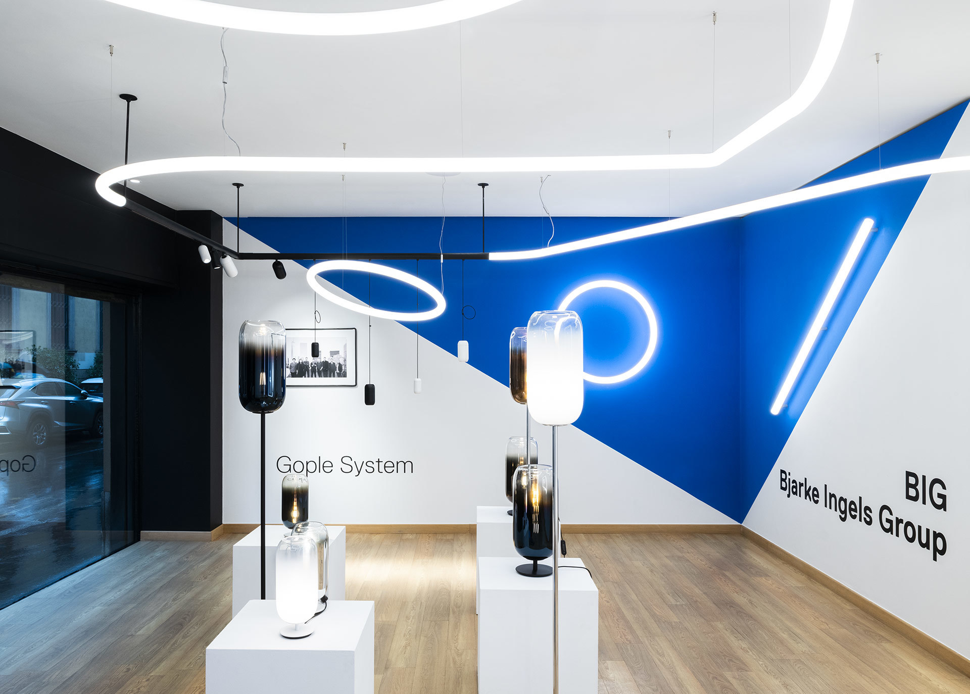 Artemide showroom displaying Gople System floor lamps and BIG Bjarke Ingels Group circular pendant lights with linear ceiling installations