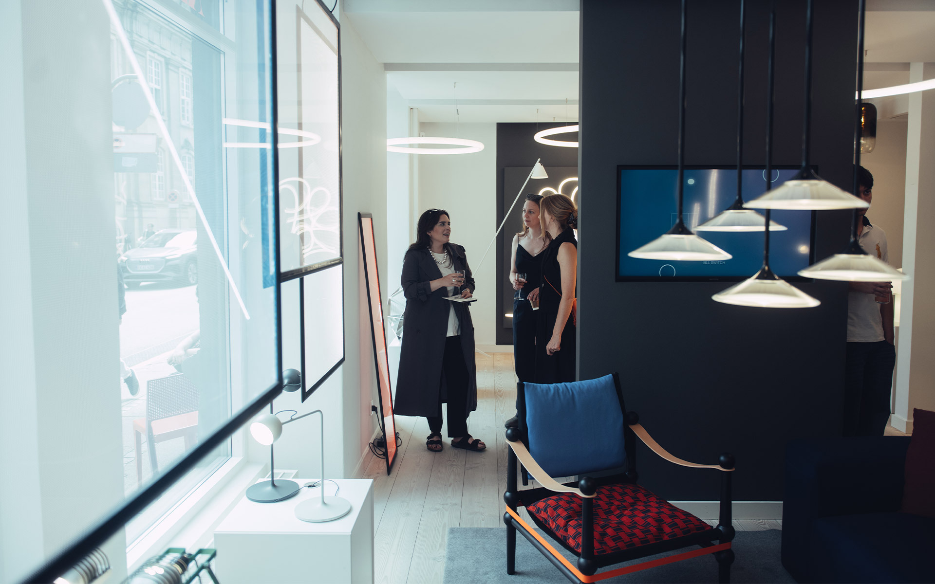Two women consulting in an Artemide showroom displaying pendant, table, and circular LED lamps across a modern interior.
