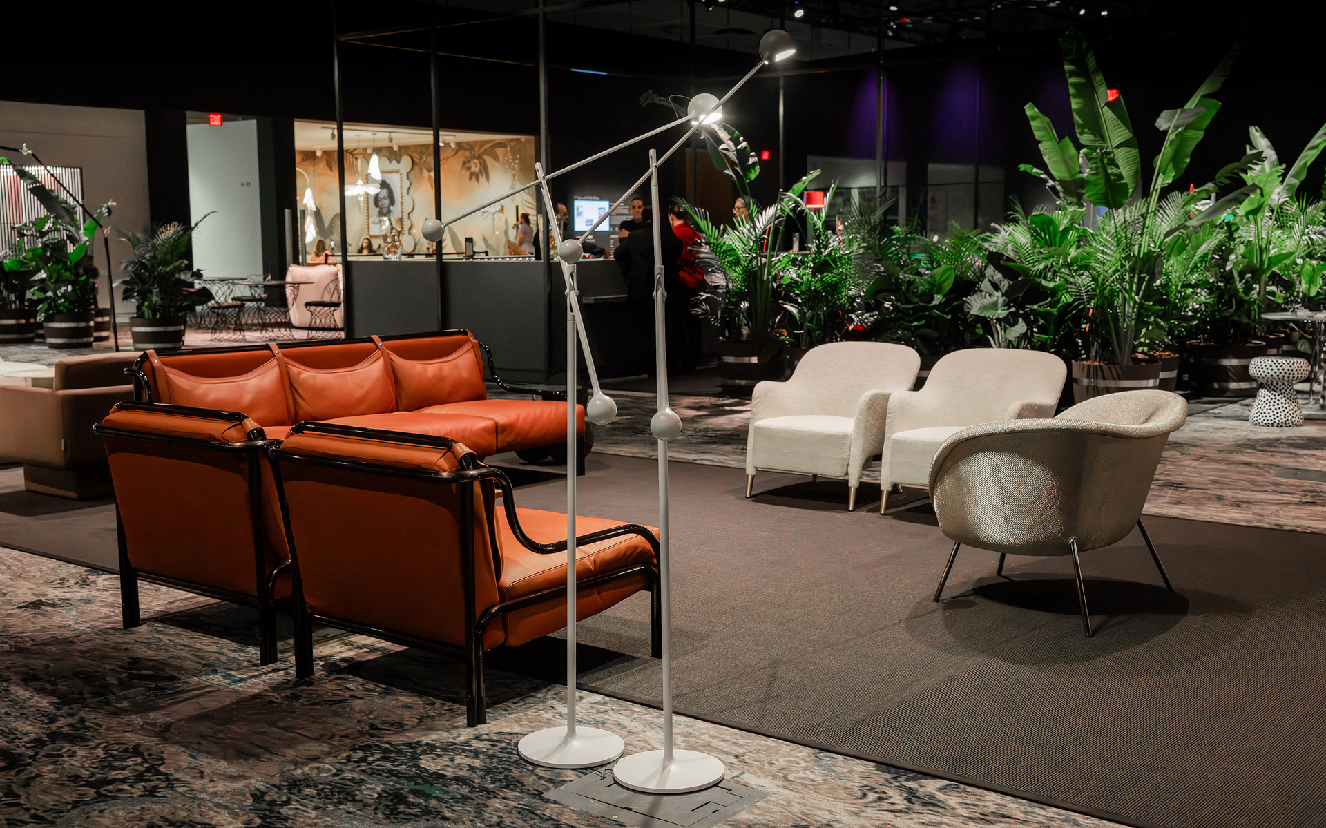 Artemide floor lamp with adjustable arm in a showroom setting, alongside leather sofas and white armchairs amid lush greenery.