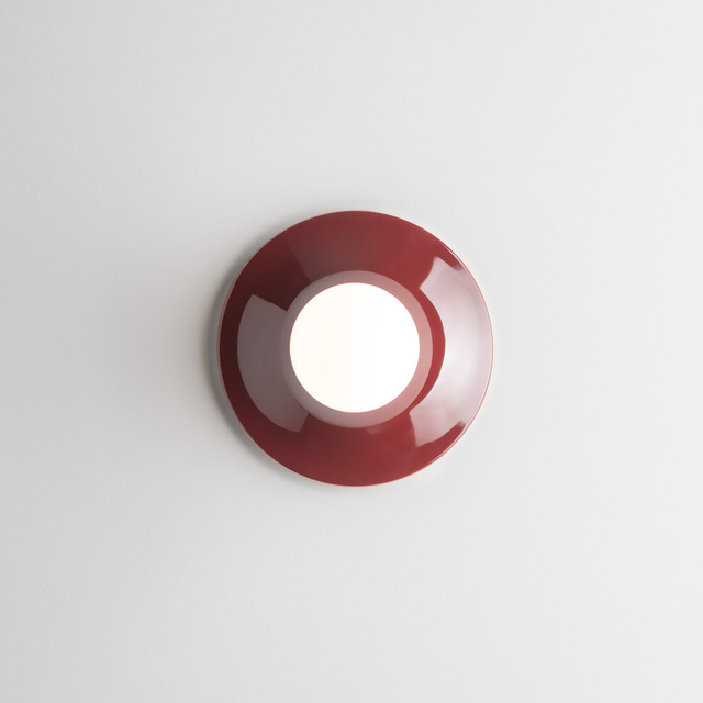 Bordeaux Teti wall lamp with a lit spherical bulb, mounted on a white wall.
