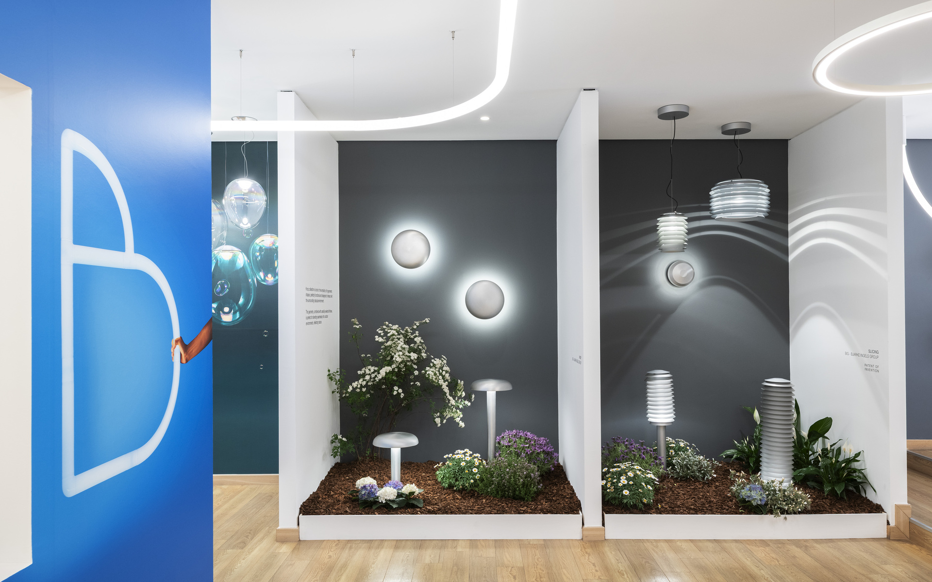 Artemide showroom display with outdoor lighting: wall-mounted globe lights, pendant lamps, and garden path fixtures among plants