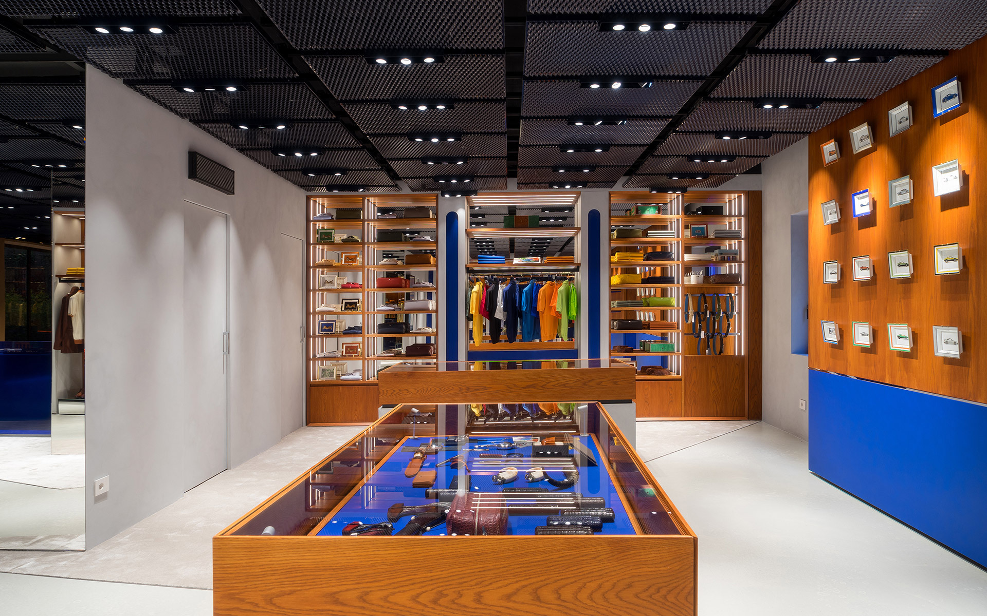 Modern retail store interior with recessed ceiling spotlights illuminating wood display shelves, colorful merchandise, and a central glass showcase.