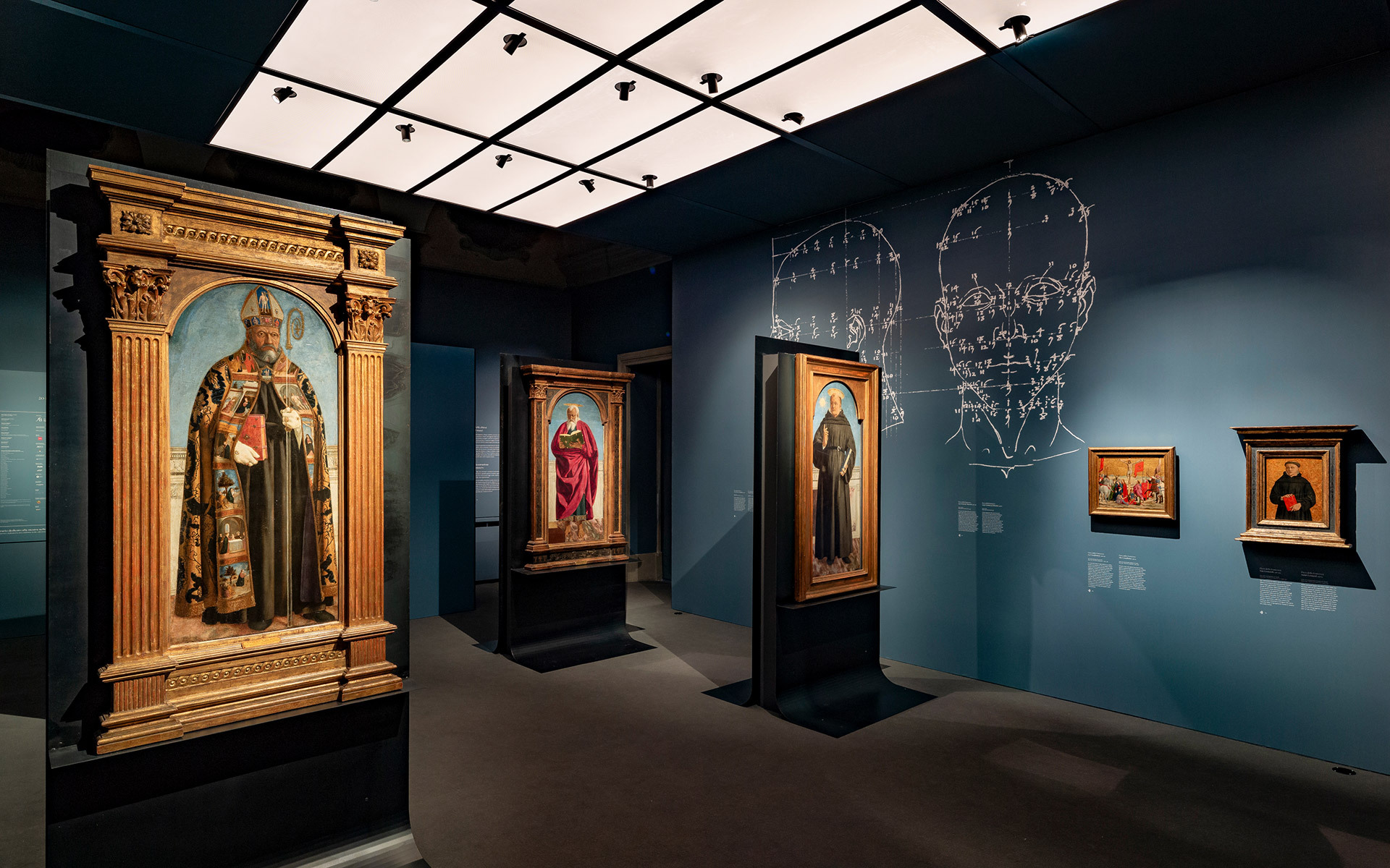 Museum gallery with Renaissance paintings on dark teal walls, illuminated by Artemide ceiling spotlights on a grid track system.