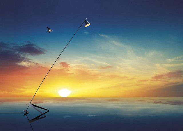 Artemide floor lamp with slim diagonal stem and adjustable head, reflected on water surface against a vibrant sunset sky.
