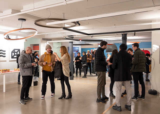 Groups of people networking at an indoor event, with Artemide circular pendant lights and track lighting illuminating the space.