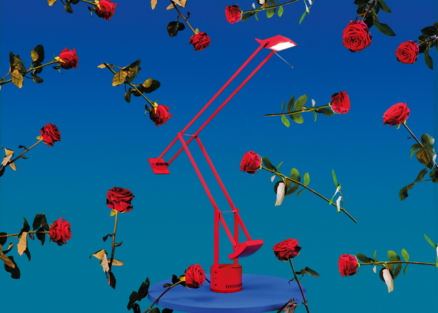 Artemide Tizio red desk lamp with adjustable arms on blue base, surrounded by floating red roses on blue background