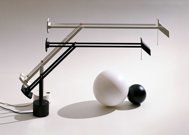 Artemide Tizio desk lamp in black and silver with adjustable arms, displayed alongside a large white and a small black sphere