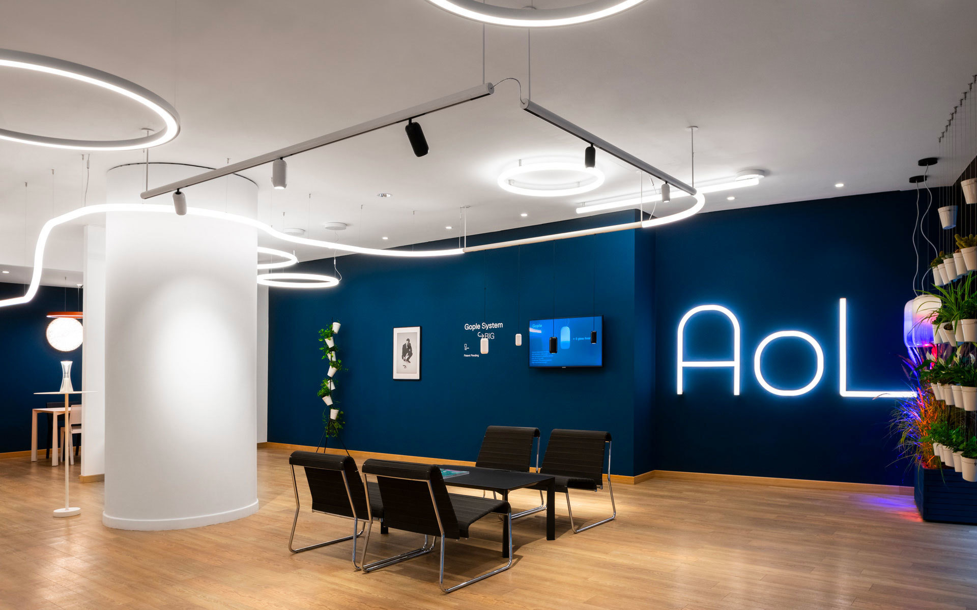 Modern AOL office with circular LED pendant lights and track lighting over a meeting table, against a deep blue branded wall