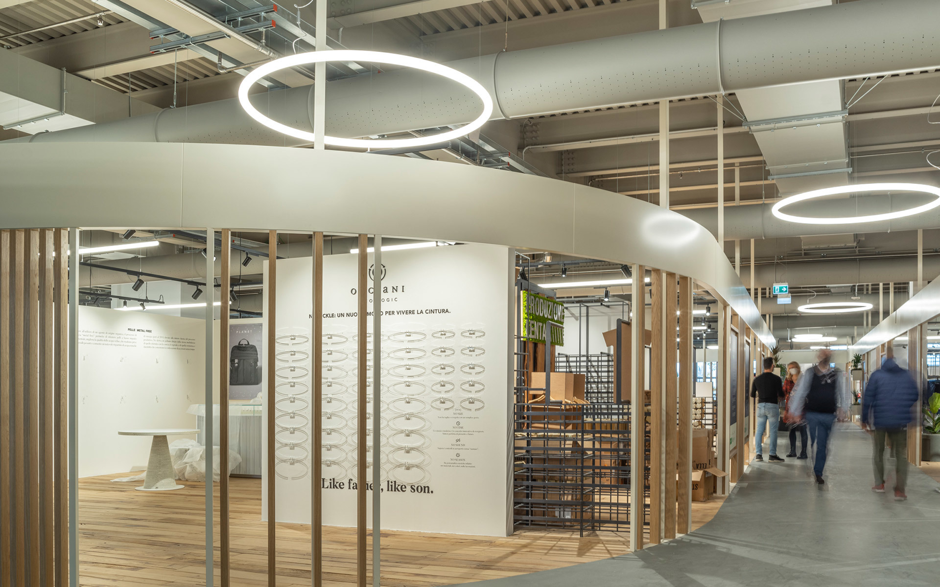Retail space with circular Artemide pendant ring lights illuminating a fashion boutique with wooden columns and display walls.