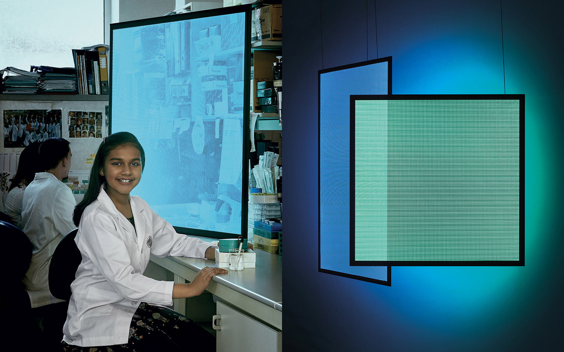 Student in lab coat smiling at desk beside an Artemide square LED panel lamp emitting teal light, mounted on dark wall