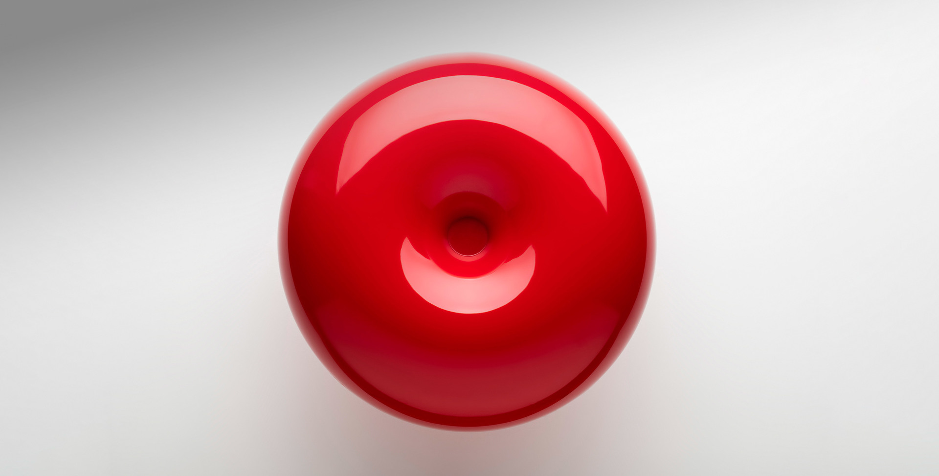 Artemide red glossy spherical lamp seen from above, featuring a concave circular opening at the center