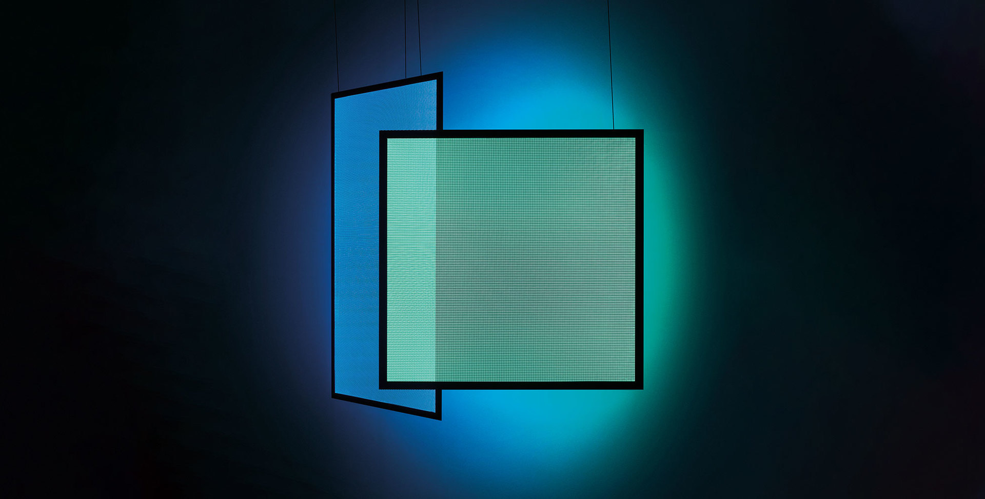 Two overlapping square pendant lamps with black frames emitting vibrant blue and teal-green light against a dark background