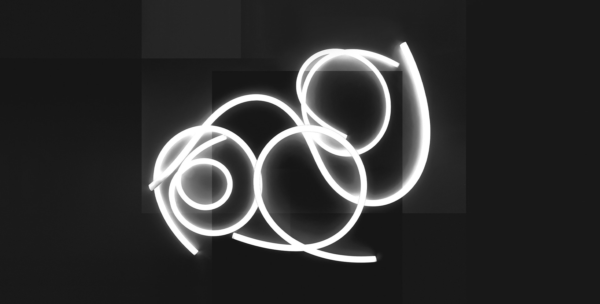 Artemide light installation with glowing white neon tubes forming overlapping spirals and loops against a dark background