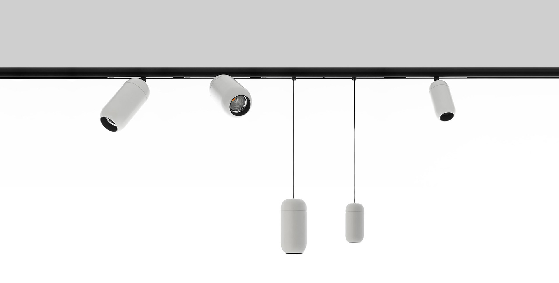 Black track system with three white cylindrical spotlights and two white capsule pendant lights hanging on thin cables.