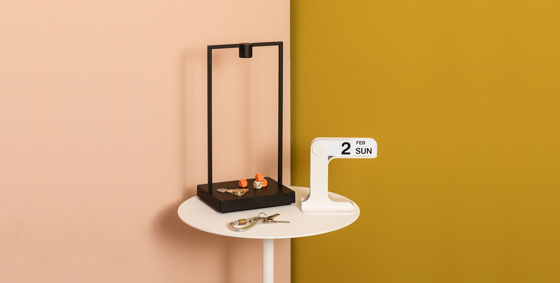 Black rectangular table lamp with minimalist frame on white side table, styled with small decorative objects and a calendar showing Sunday Feb 2