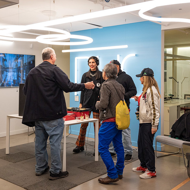 People networking in a modern showroom under Artemide circular LED pendant lights illuminating the bright open space.