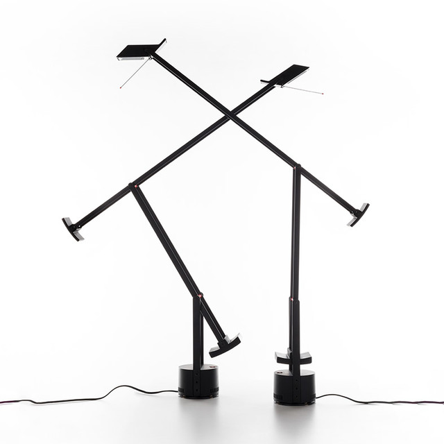 Two Artemide Tizio black desk lamps with counterbalanced arms crossed, showcasing adjustable positions on circular bases.