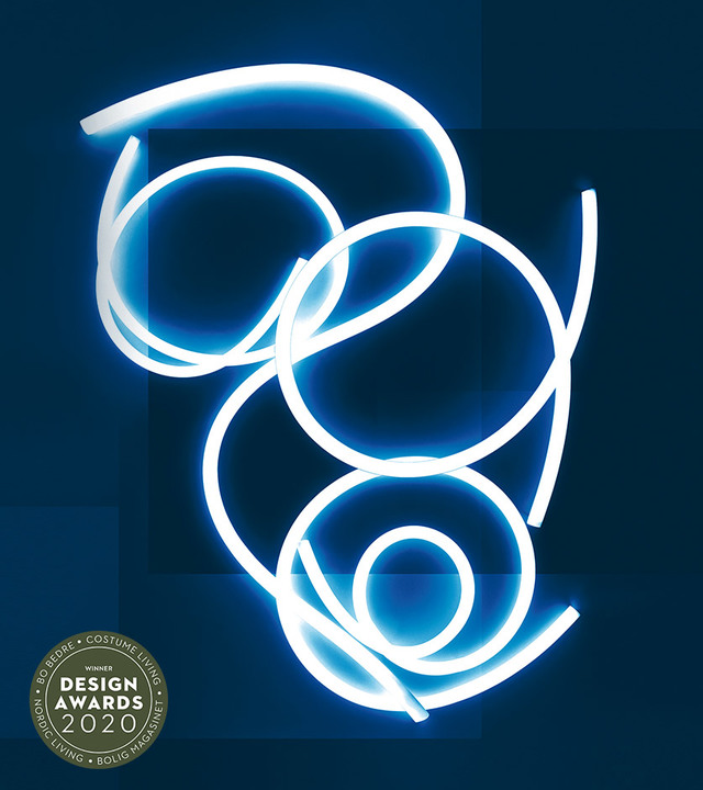 Artemide flexible LED light tube twisted into flowing loops and spirals, glowing blue-white against dark background. Design Awards 2020 winner.