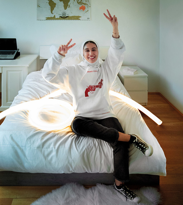 Person sitting on a bed surrounded by Artemide flexible LED light tubes forming a glowing loop on white bedding