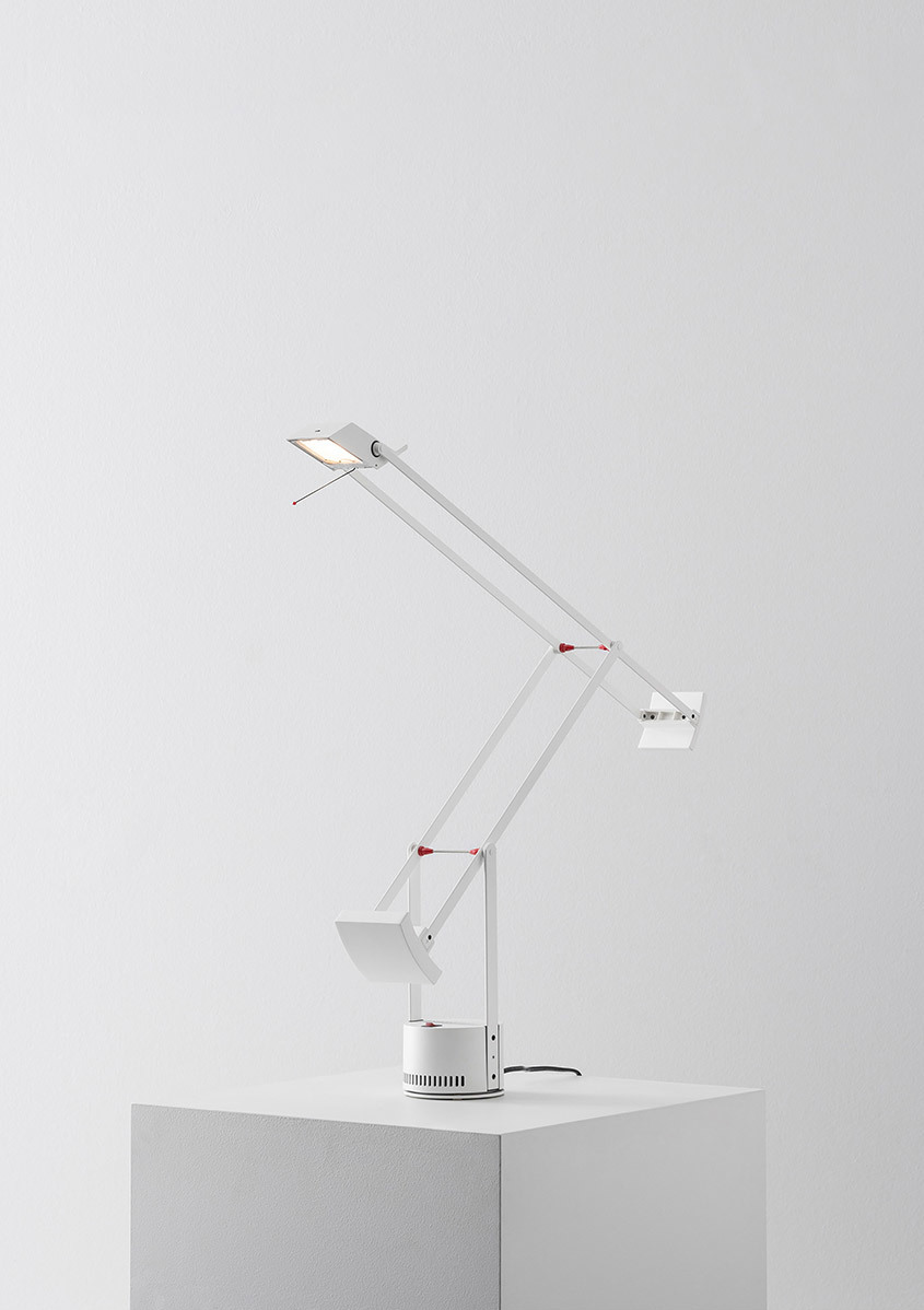 Artemide Tizio white desk lamp with articulated arms, red joints, counterweight, and rotating base on a white pedestal