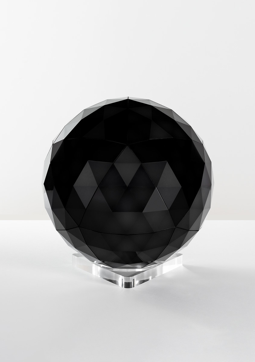 Artemide black faceted spherical lamp with geometric diamond-cut surfaces on a transparent acrylic base