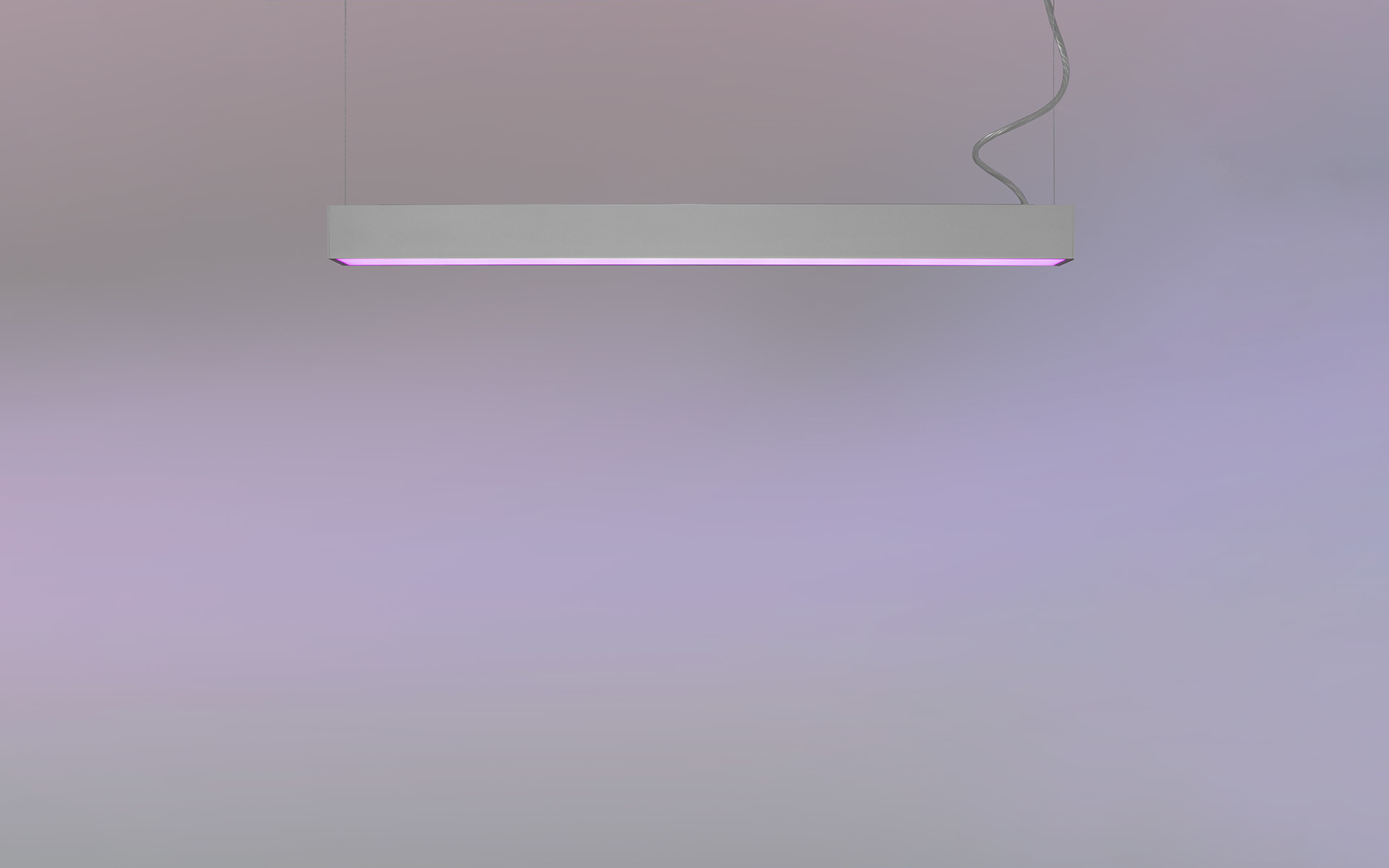 Slim white rectangular pendant lamp emitting a soft pink-purple underglow, suspended by a single cable against a neutral background