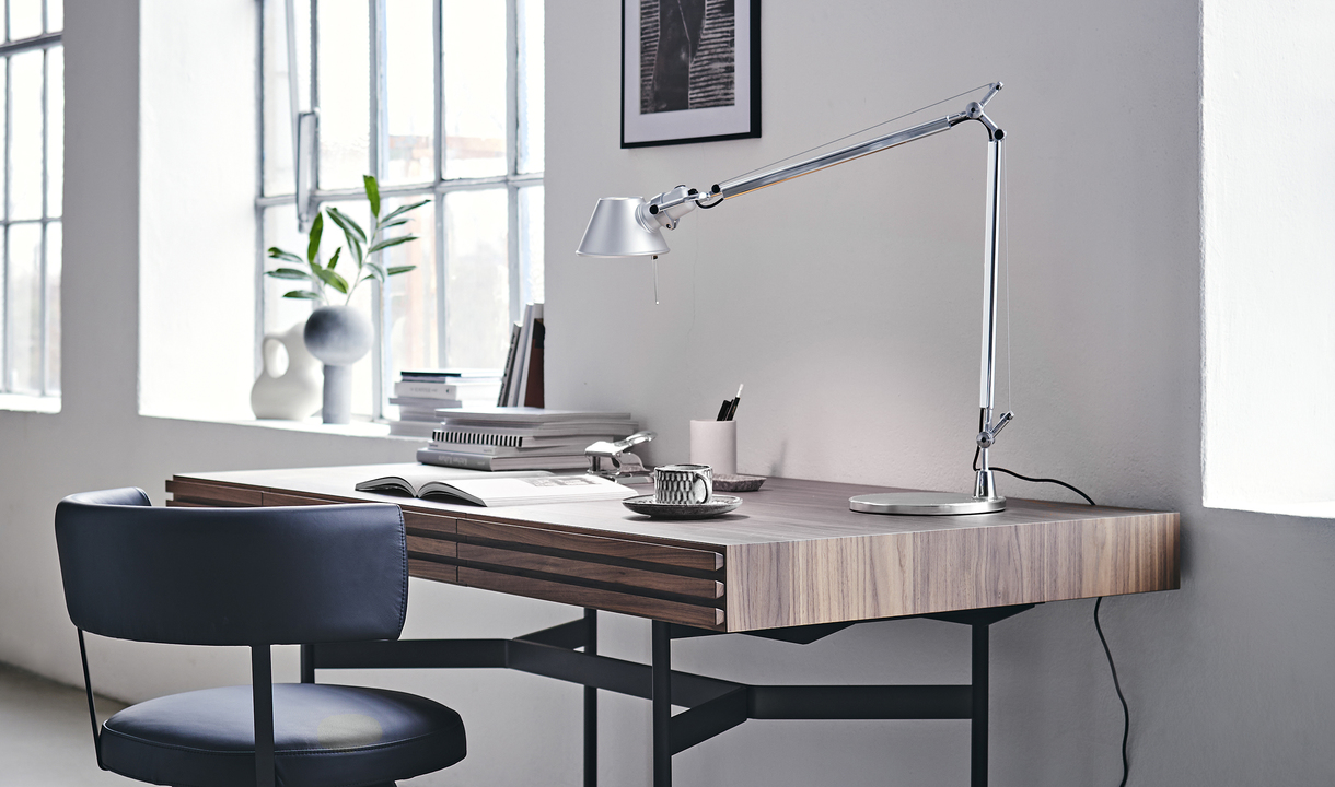 Artemide Tolomeo desk lamp in aluminum on a modern wood desk in a bright home office with chair and decorative items