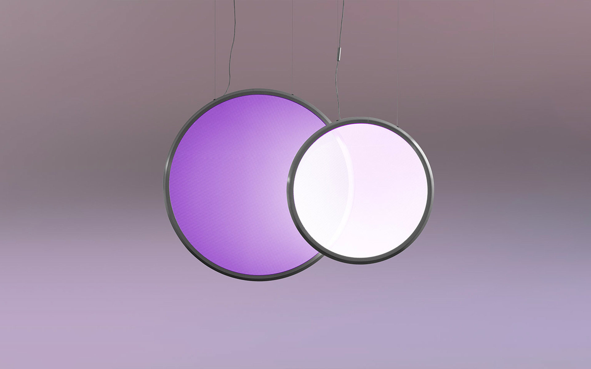 Two overlapping circular pendant lamps with dark frames: left emits purple light, right emits white-pink light, suspended by thin cables