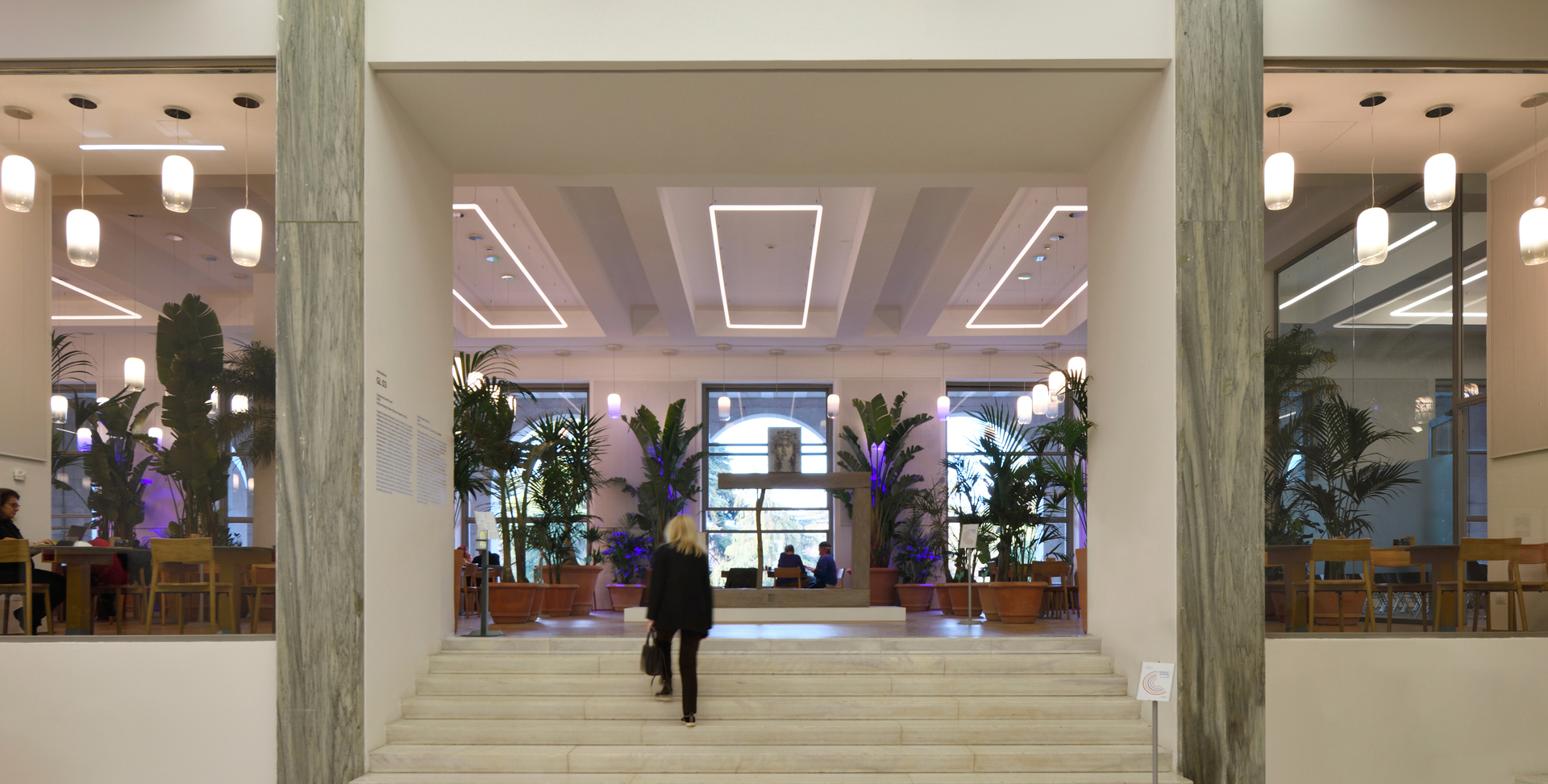 Grand lobby entrance with marble columns, steps, and Artemide pendant lights illuminating the space with warm, elegant lighting.