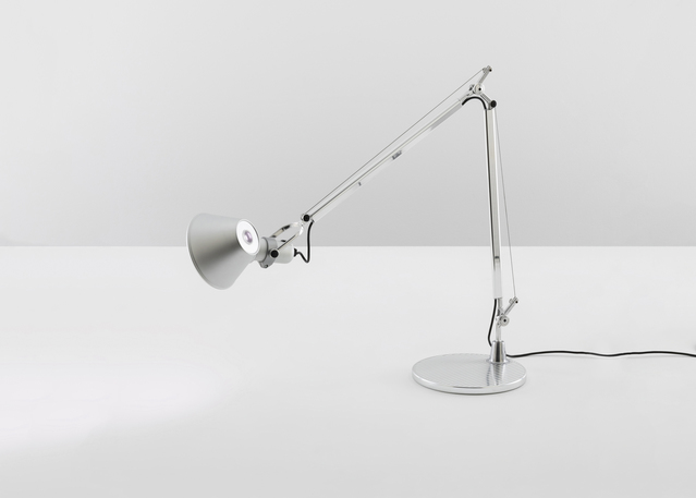 Artemide Tolomeo desk lamp in polished aluminum with adjustable articulated arm, conical shade, and circular base on white surface