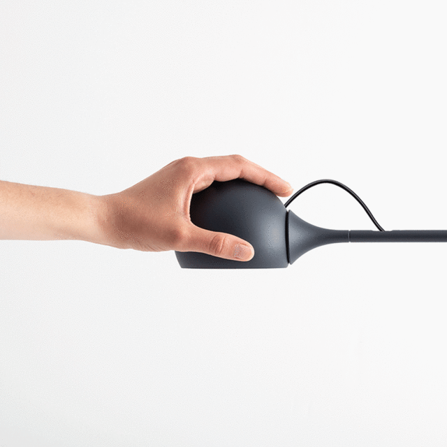 Hand adjusting the dark grey spherical head of a floor lamp, demonstrating its orientable positioning feature.