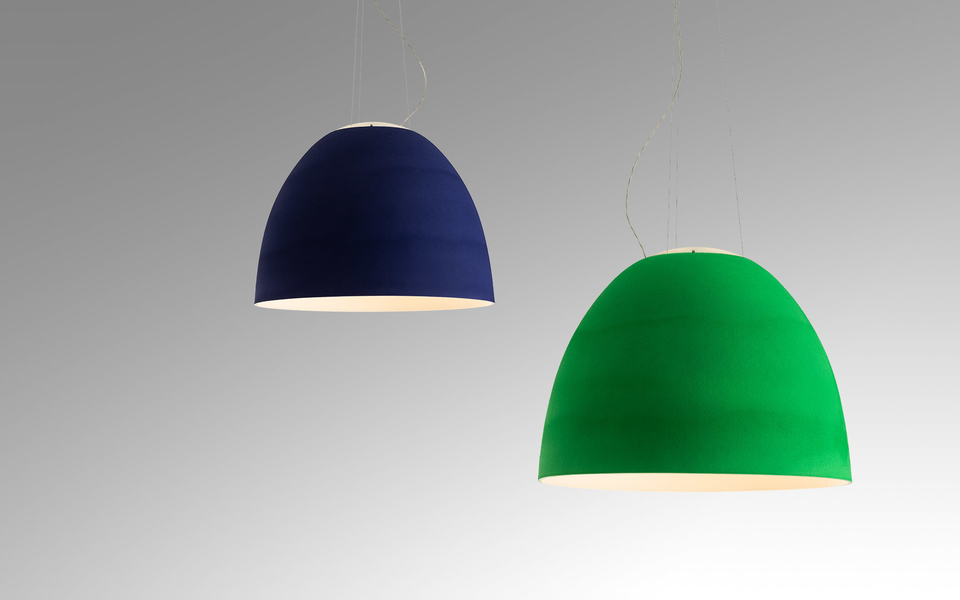 Two Artemide pendant lamps with bell-shaped shades: left in deep blue, right in vivid green, emitting warm light downward.
