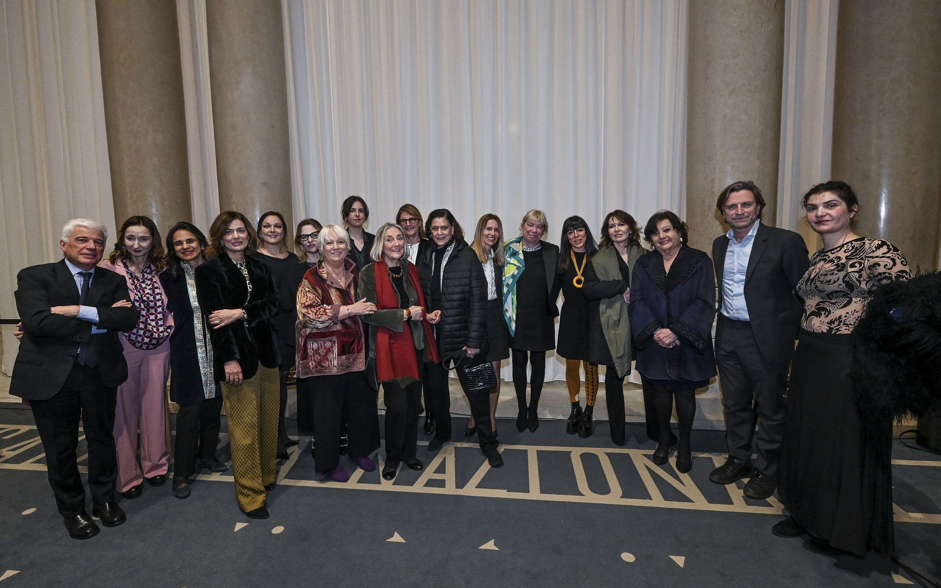 Group of approximately twenty professionals posing together for a formal group photo in an elegant hall.