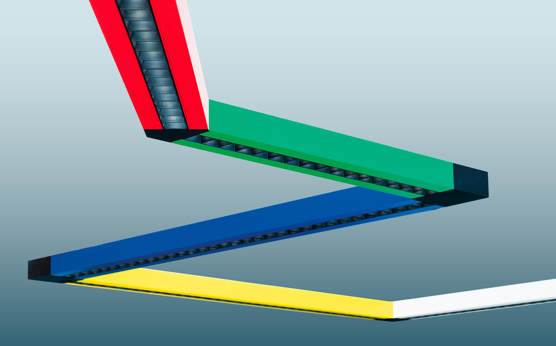Artemide modular linear LED light system with four angular segments in red, green, blue, and yellow, forming a zigzag pattern