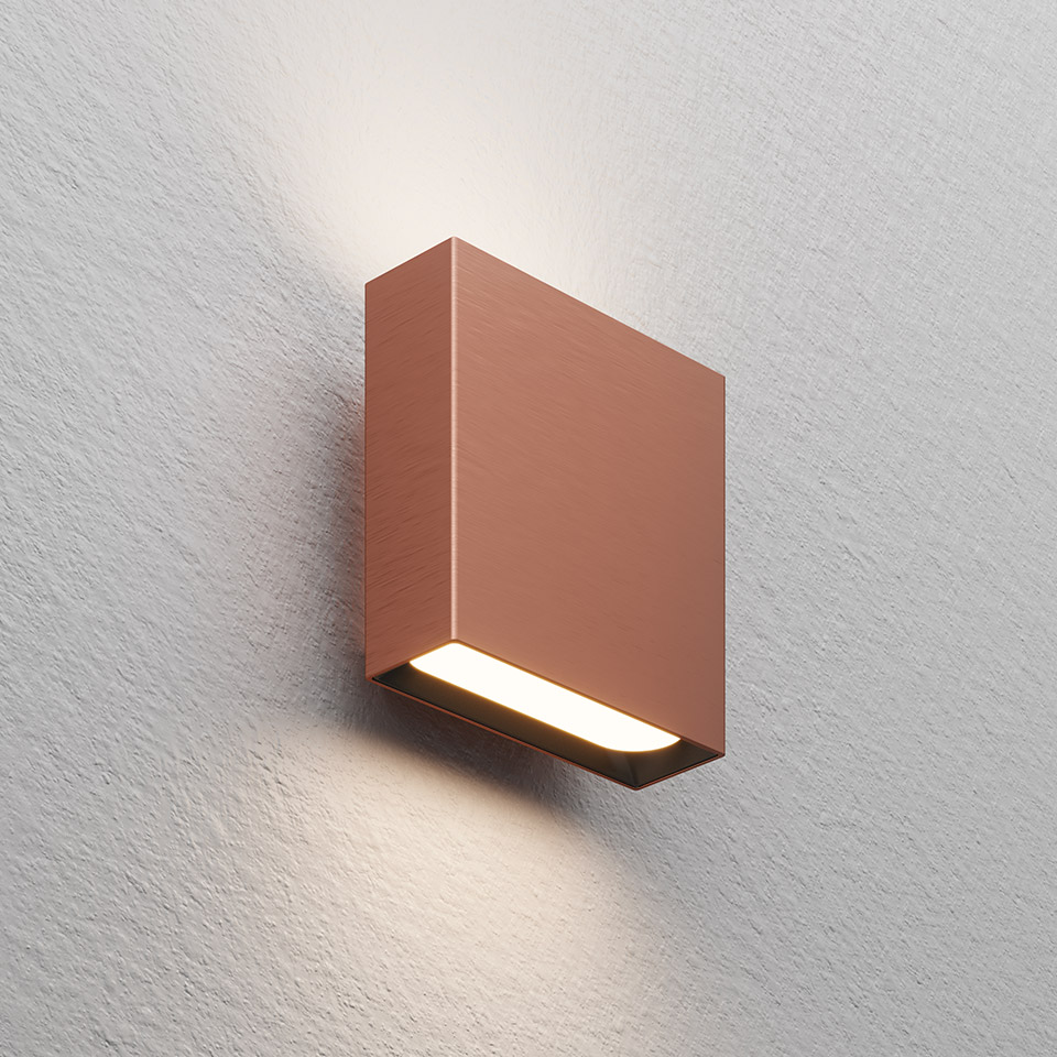 Artemide Agathe wall lamp in copper finish, square body emitting warm white light downward and upward on textured wall