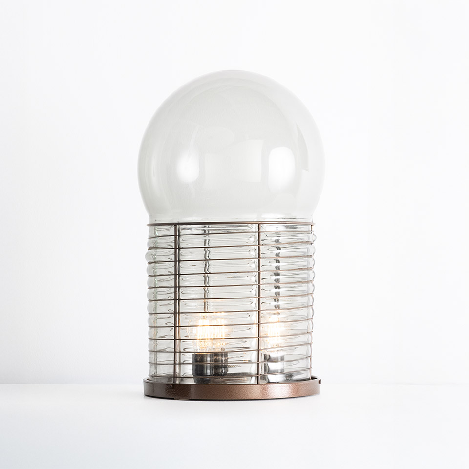 Artemide Alcinoo table lamp: clear glass dome top over ribbed cylindrical glass body with metallic bronze base and visible filament bulb