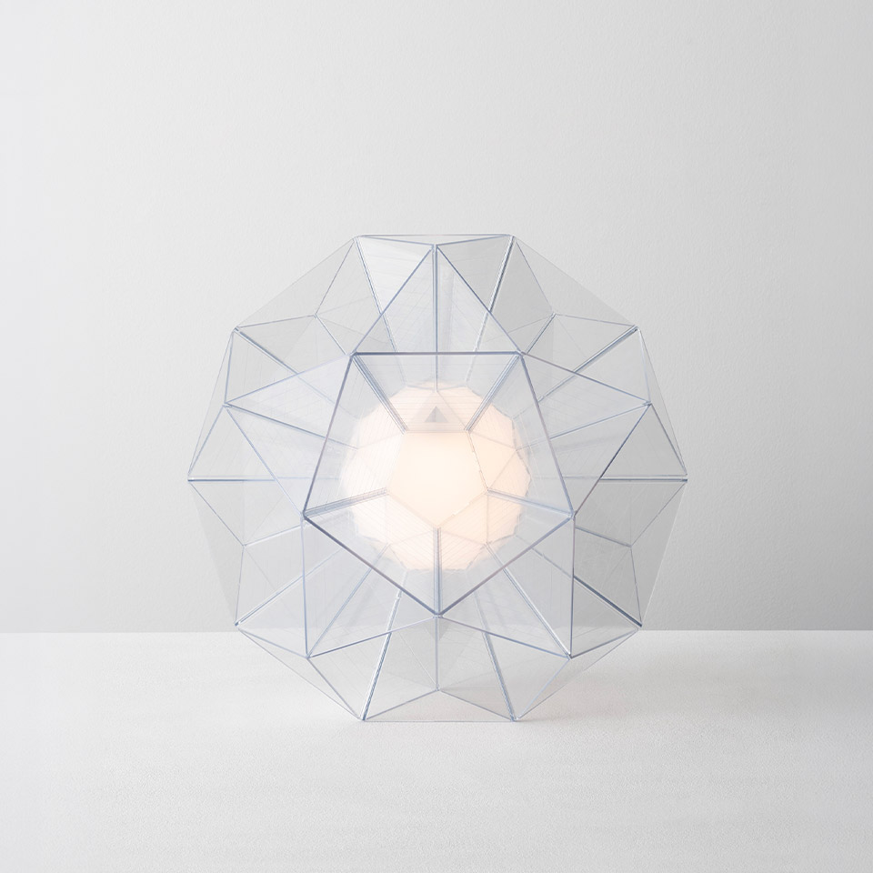 Artemide Arctic table lamp: geometric dodecagonal transparent frame with triangular facets surrounding a central glowing opal diffuser