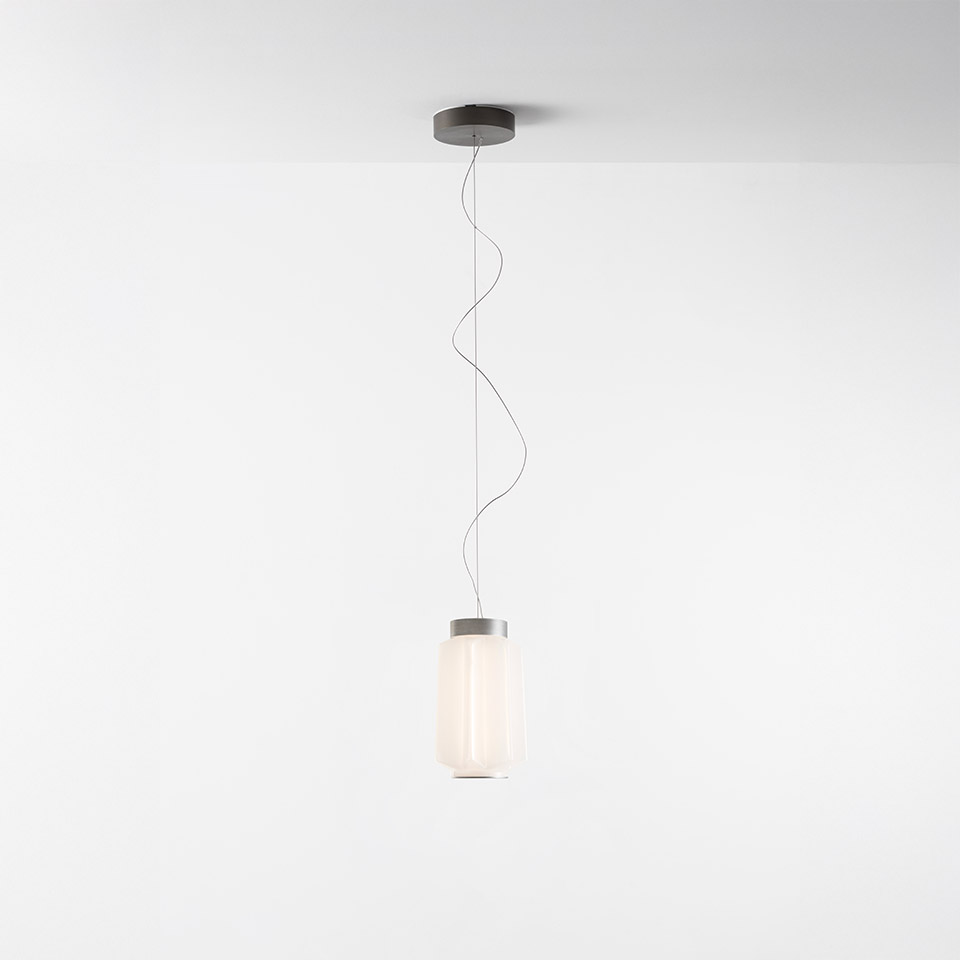 Artemide Auralia pendant lamp with cylindrical opal glass diffuser, grey metal cap, and wavy suspension cable