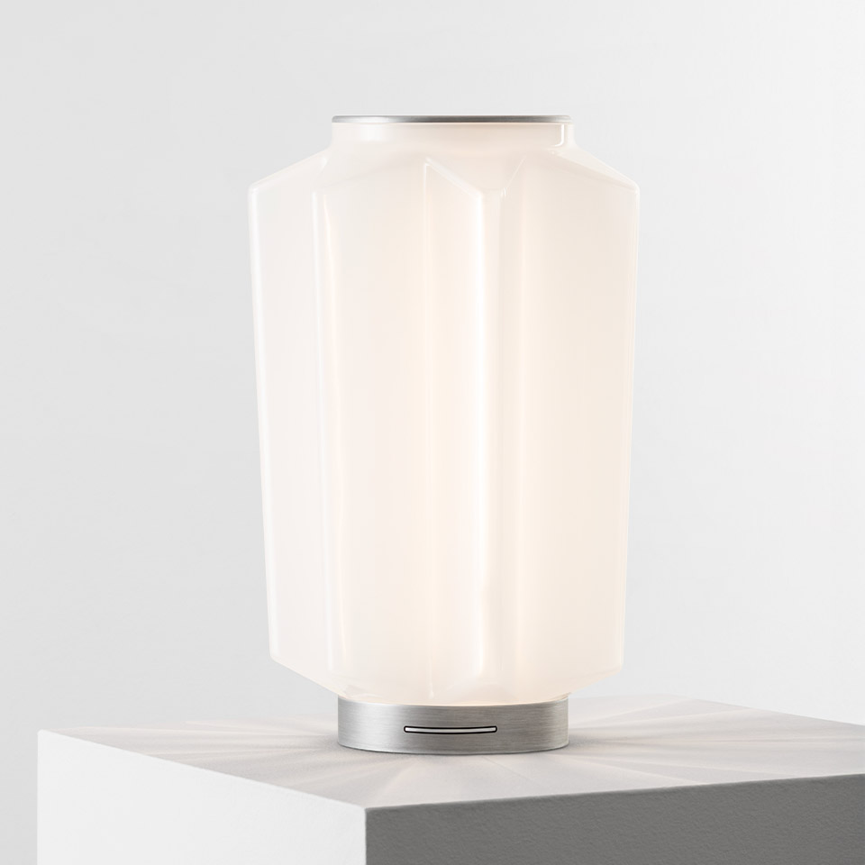 Artemide Auralia table lamp with faceted opal white glass diffuser and brushed aluminum base on marble surface