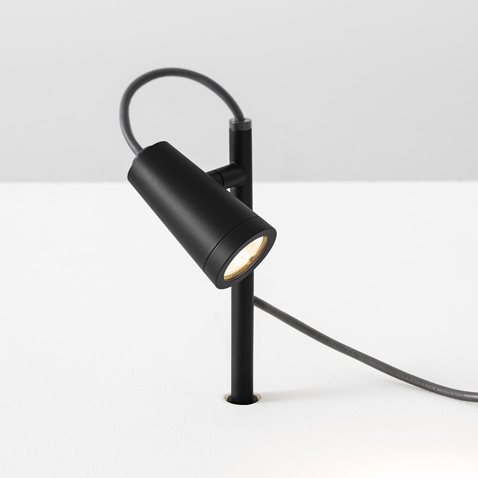 Artemide Conus spotlight in matte black, cylindrical head on angled stem with power cord, designed for accent lighting