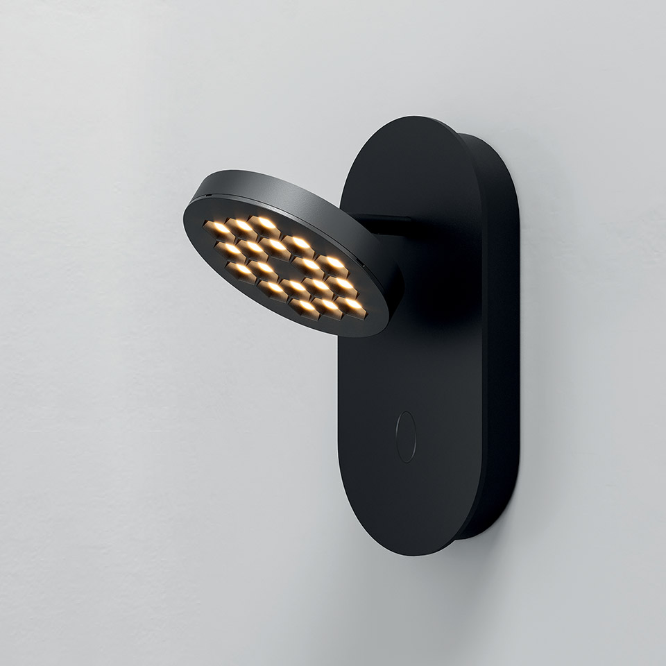 Artemide Helgoland wall lamp in black with adjustable circular LED head featuring gold reflectors, mounted on oval backplate