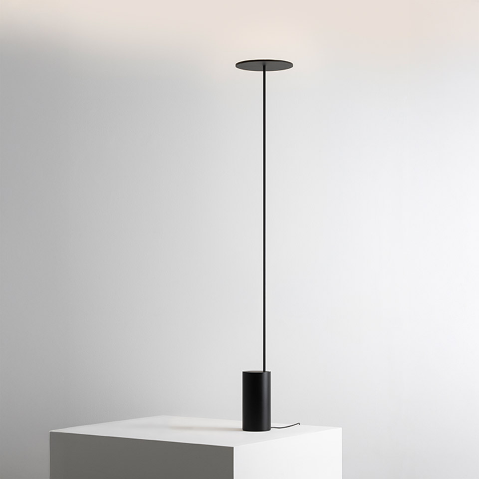 Artemide Helgoland floor lamp in black: cylindrical base on white pedestal, ultra-thin stem extending to a flat circular disc diffuser